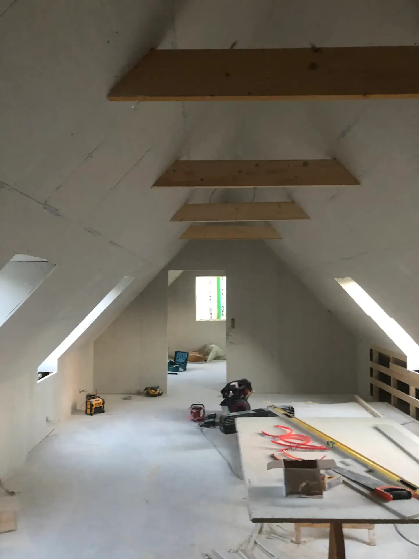 Indretning af loft med træbjælker i et nybygget værelse.