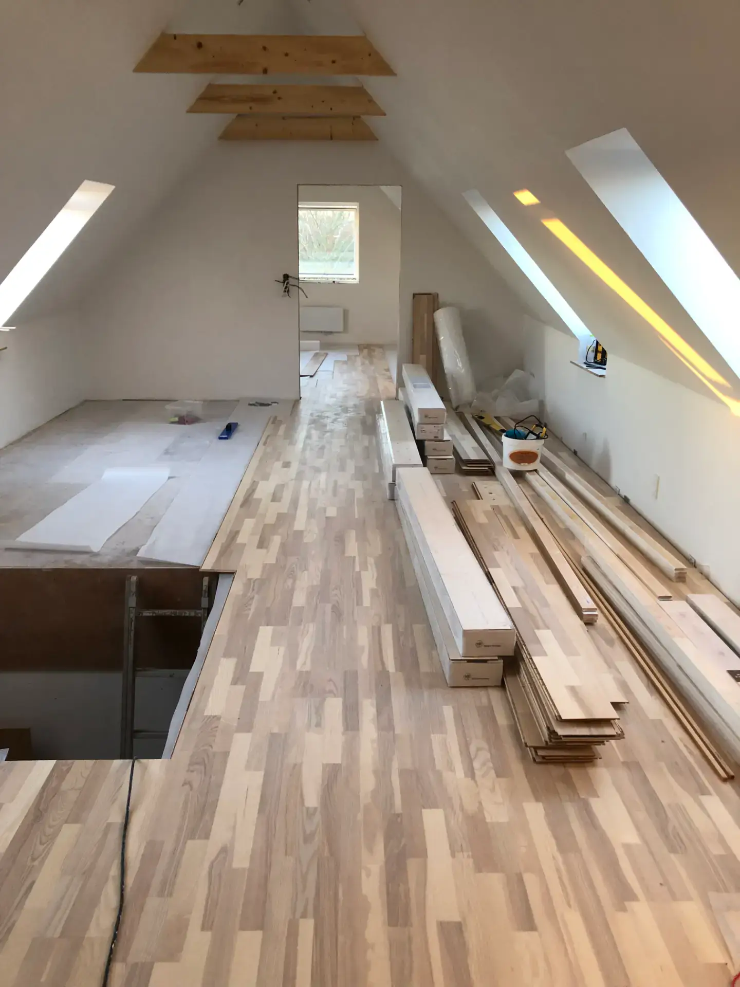 Indretning af loftsrum med nyt trægulv og tagvinduer under renovering.