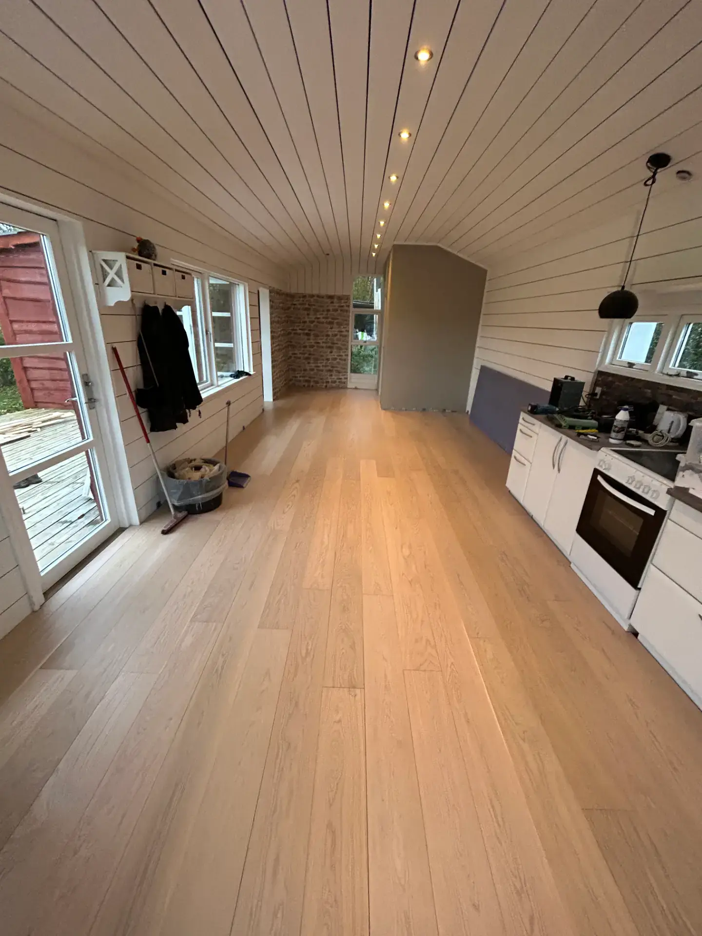 Moderne køkken med lyst trægulv og hvidt inventar.