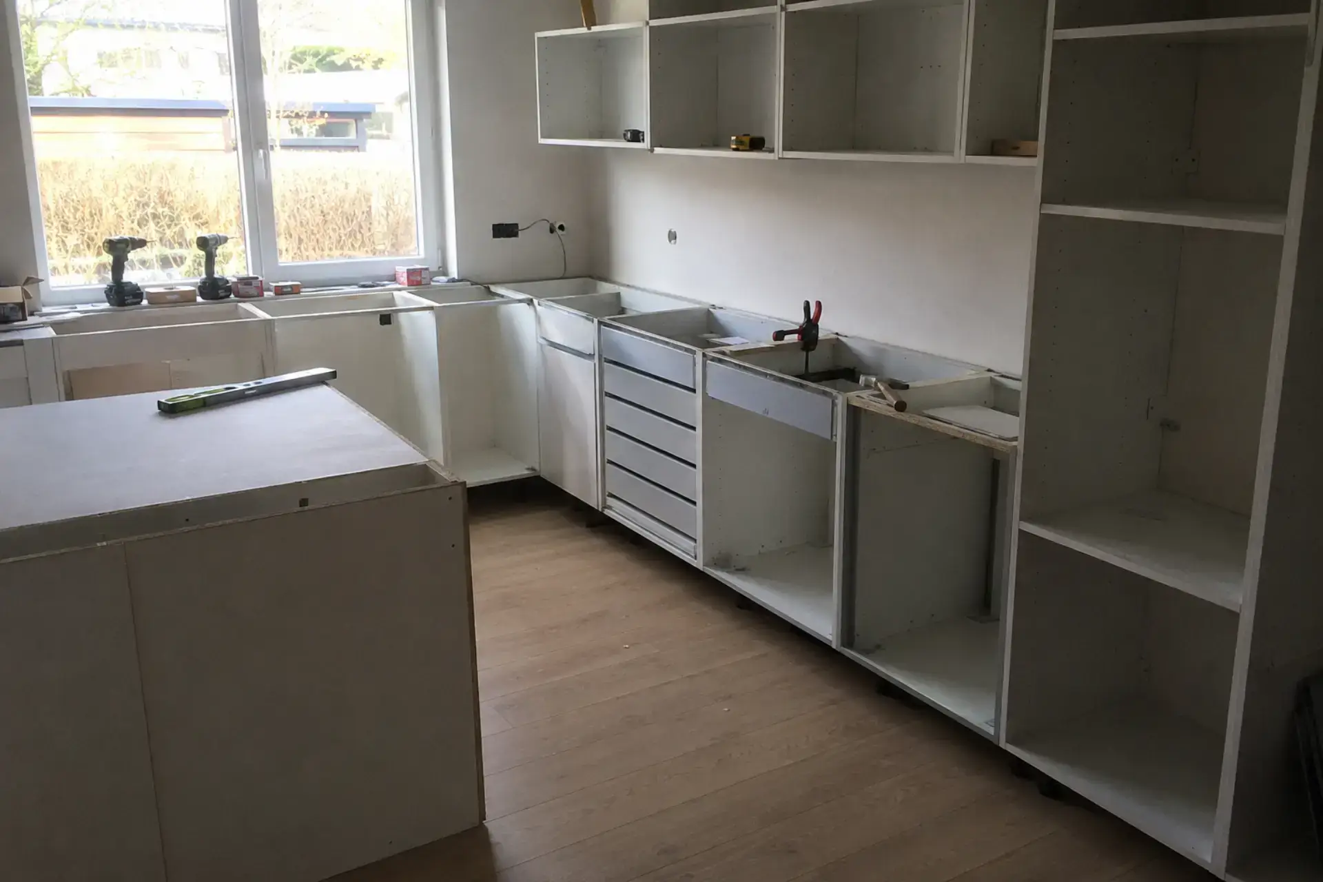 Køkkeninstallation i gang med tomme skabe og værktøj.